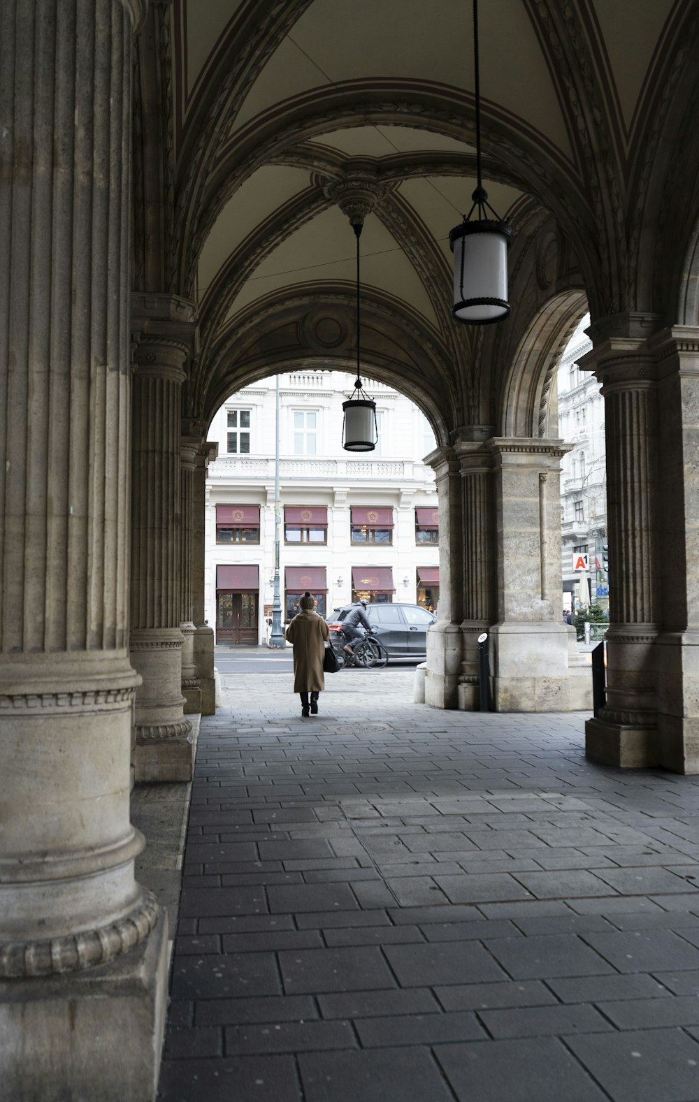 a man walking down a street next to tall pillars