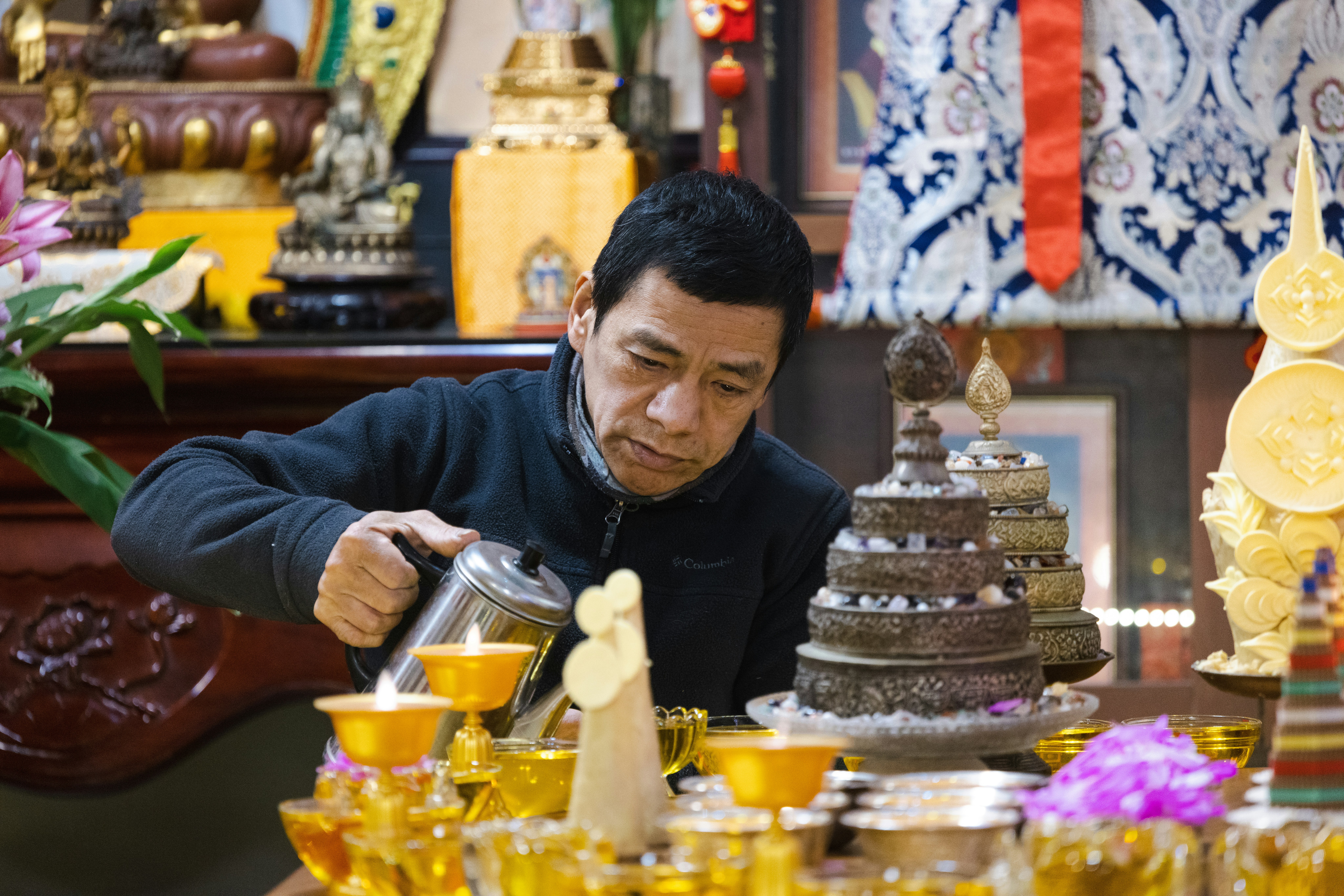 A photo showing a gold merchant weighing gold ornaments on a digital scale, with a customer watching.