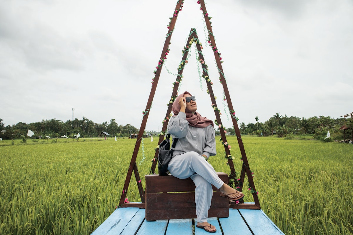 a woman sitting on a wooden platform talking on a cell phone