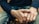 Close-up of a person's hands resting on their lap, featuring a casual attire with a dark sweater and blue jeans.