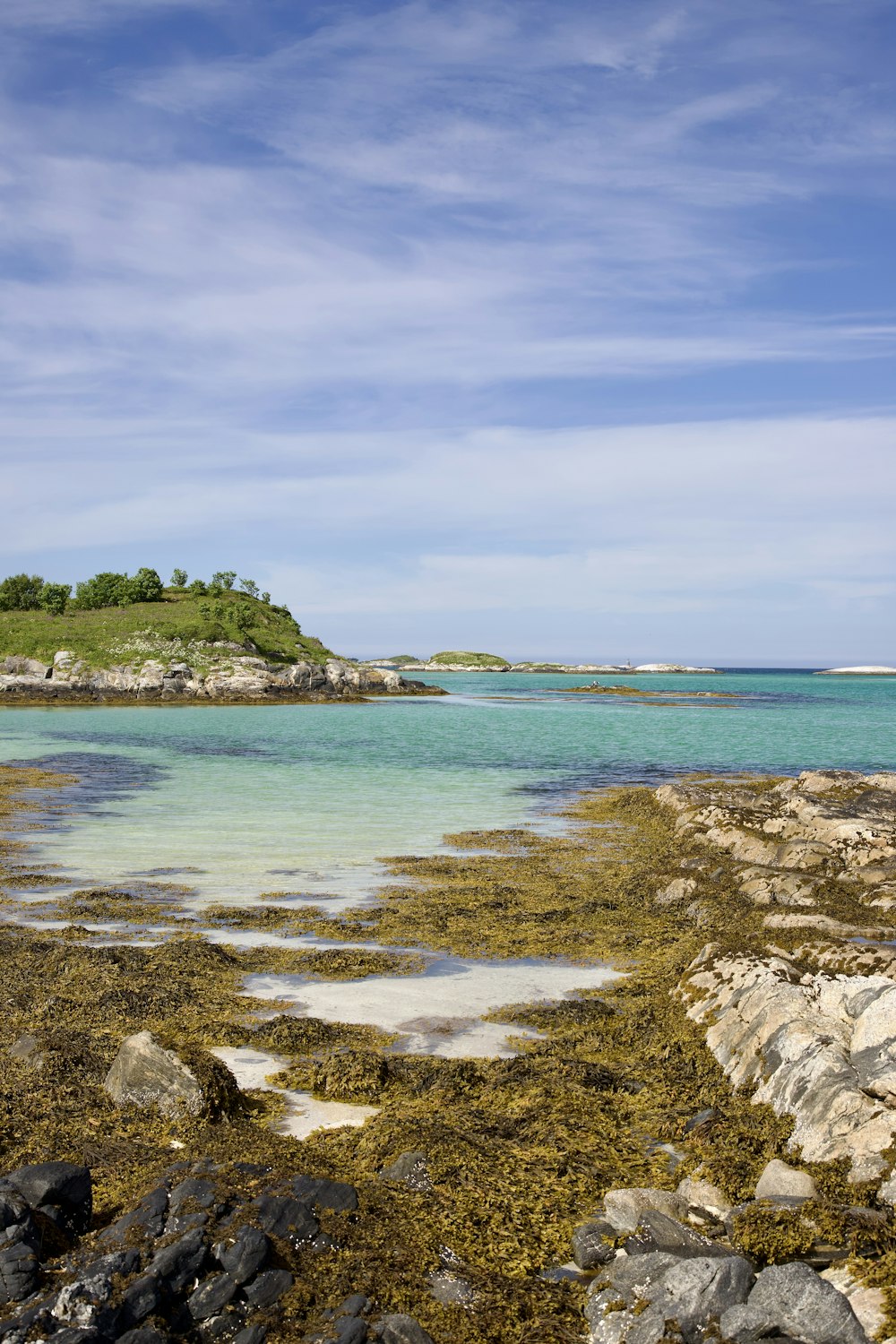 a body of water surrounded by rocks and grass