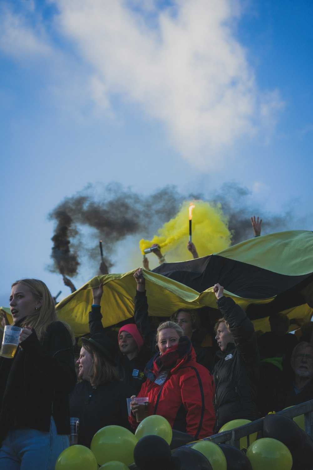 a crowd of people standing around a yellow umbrella