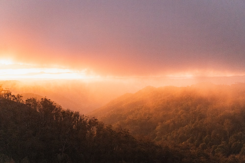 the sun is shining through the clouds over the mountains