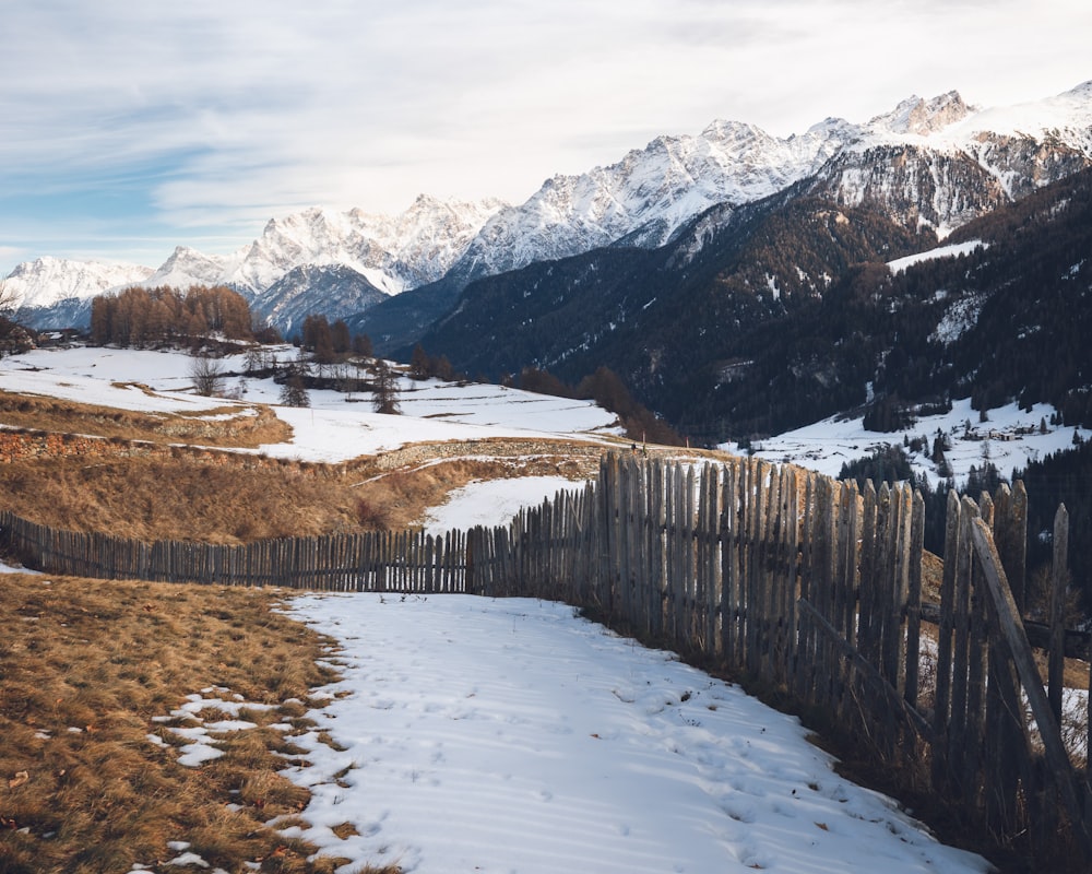 a wooden fence in the middle of a snowy field