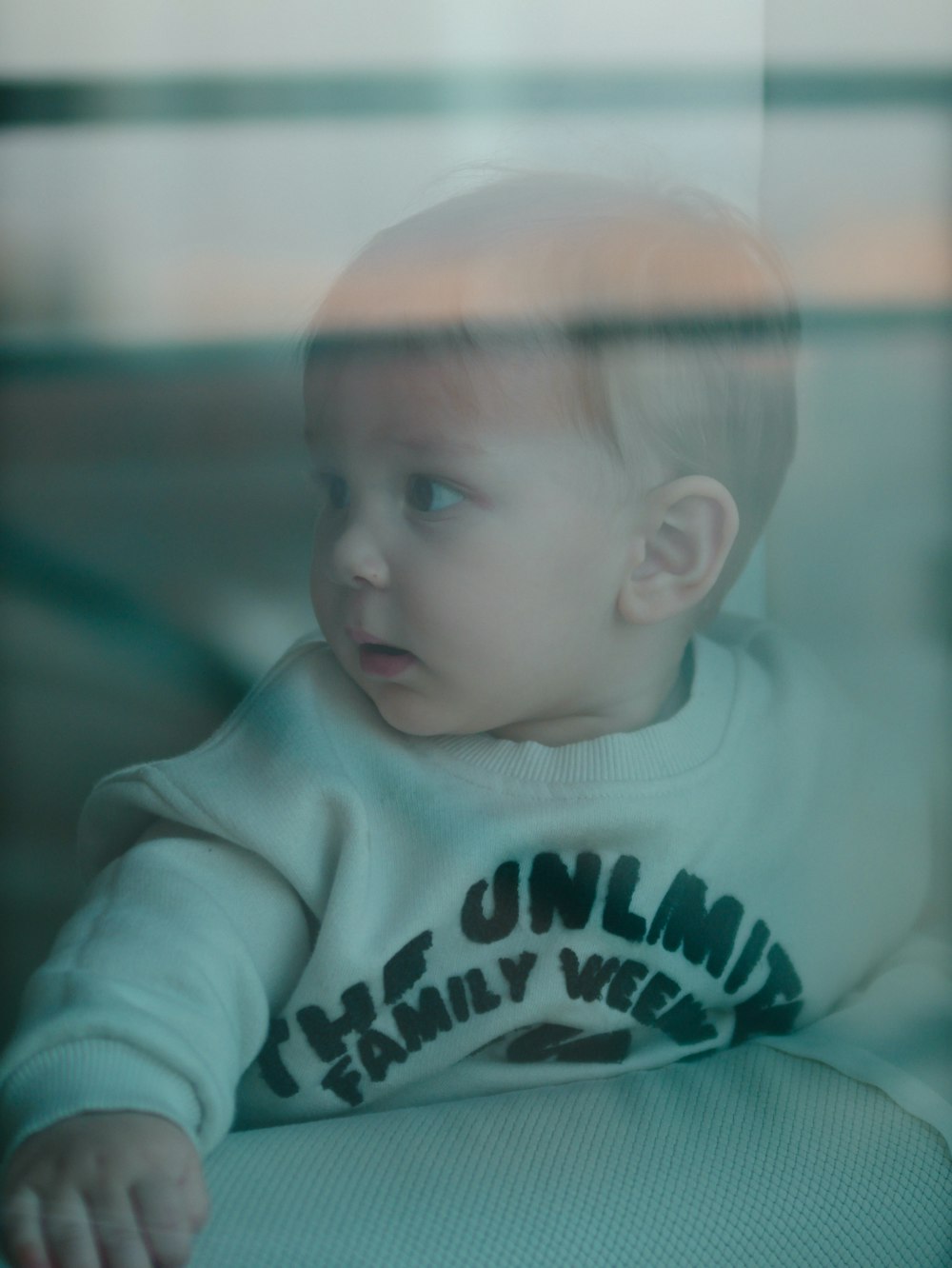 a baby sitting in a chair looking out a window
