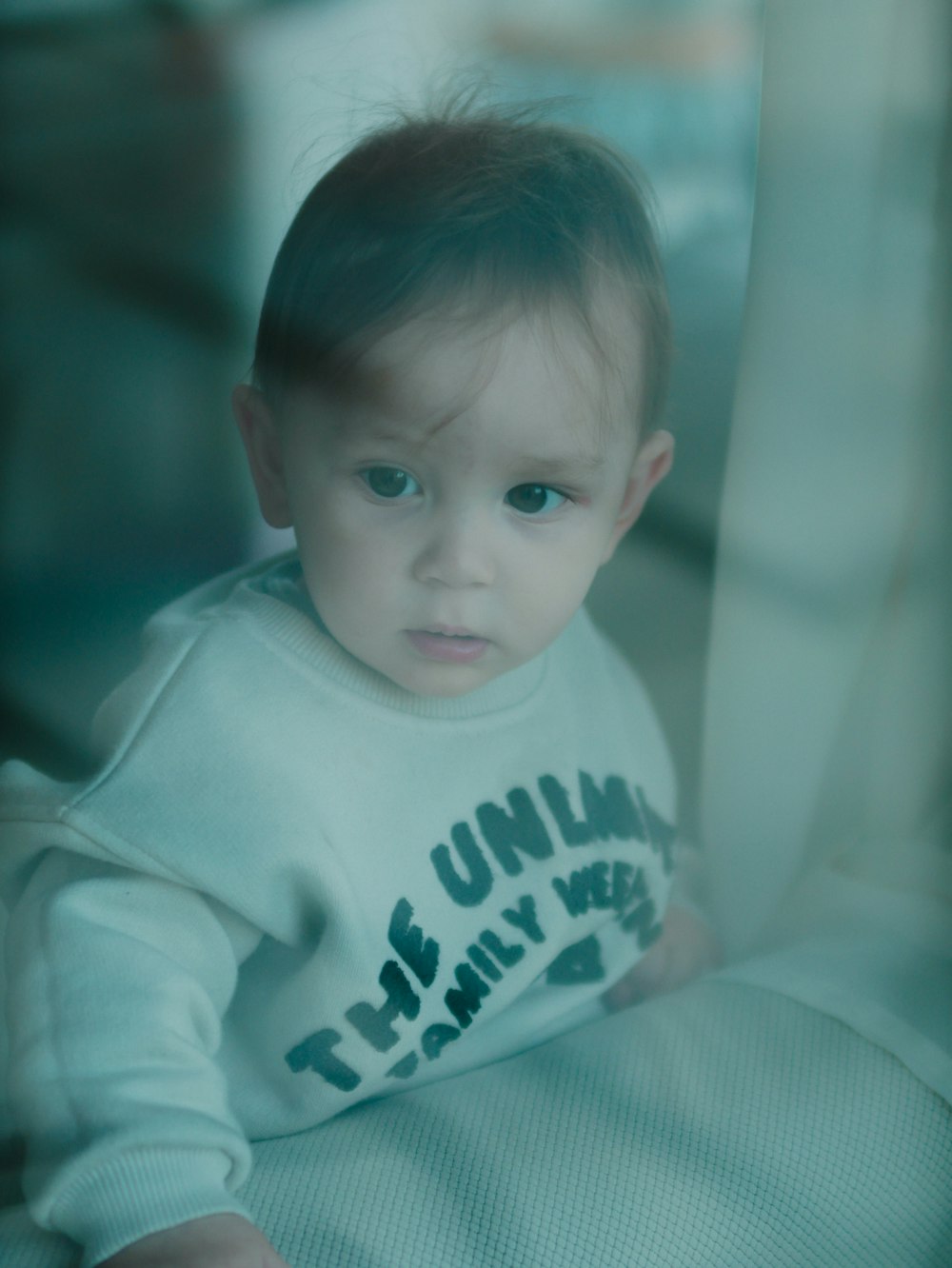 a baby sitting on a bed looking at the camera