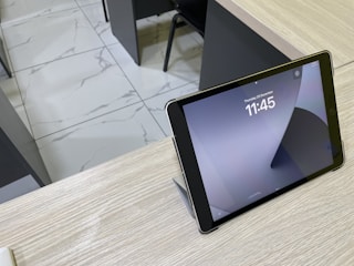 Close-up of a digital clock showing hourly updates with a background of a new home listing on a tablet.