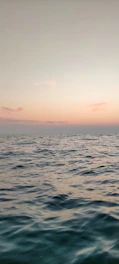 A calm beach at sunset with gentle waves and pastel skies.