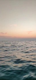 A calm beach at sunset with gentle waves and pastel skies.