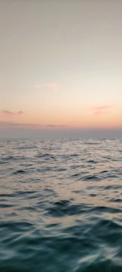 Calm waters reflecting soft pastel hues at sunset along the shore.