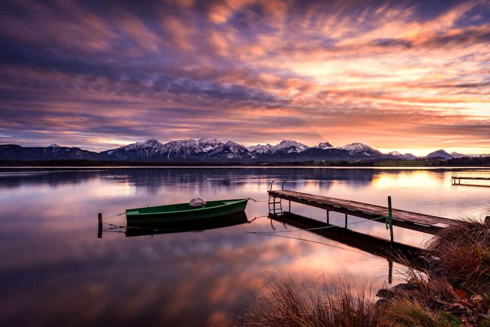 a green boat sitting on top of a body of water