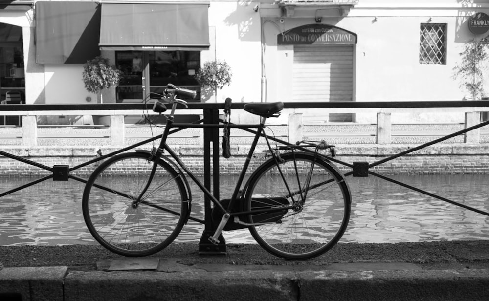 a black and white photo of a bicycle leaning against a fence