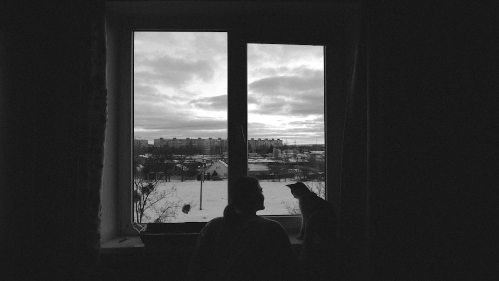 a person looking out a window at a snowy city