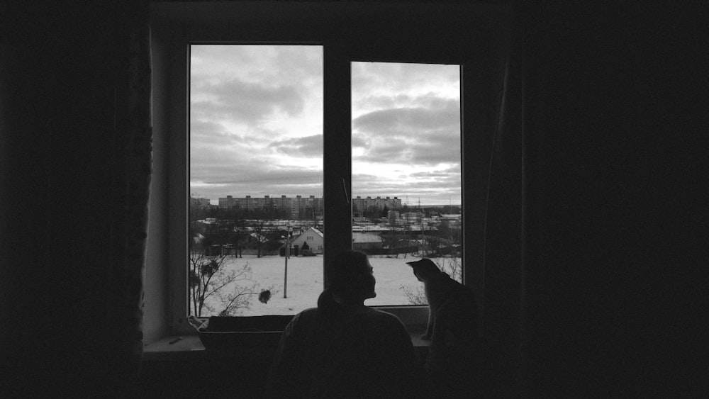 une personne regardant par la fenêtre une ville enneigée
