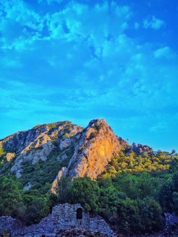 Golden sunlight bathes the ancient ruins of Bamiyan, framed by towering cliffs.