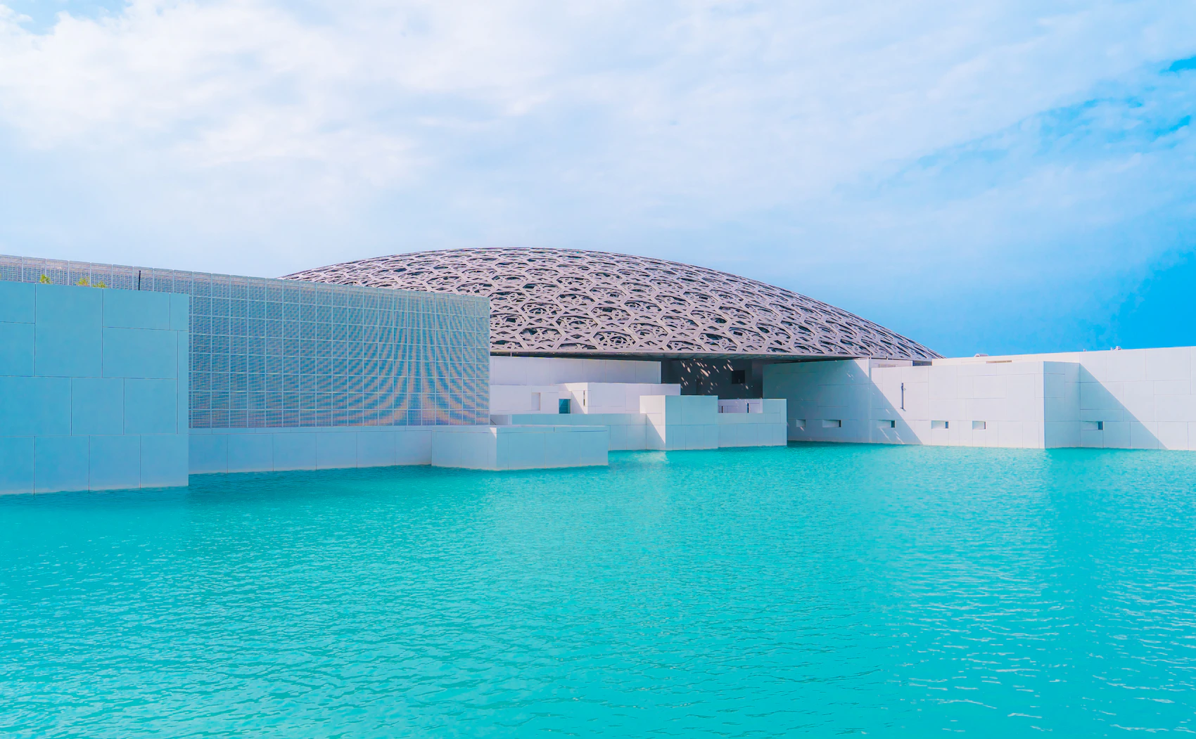 The patterned dome of Louvre Abu Dhabi above turquoise water