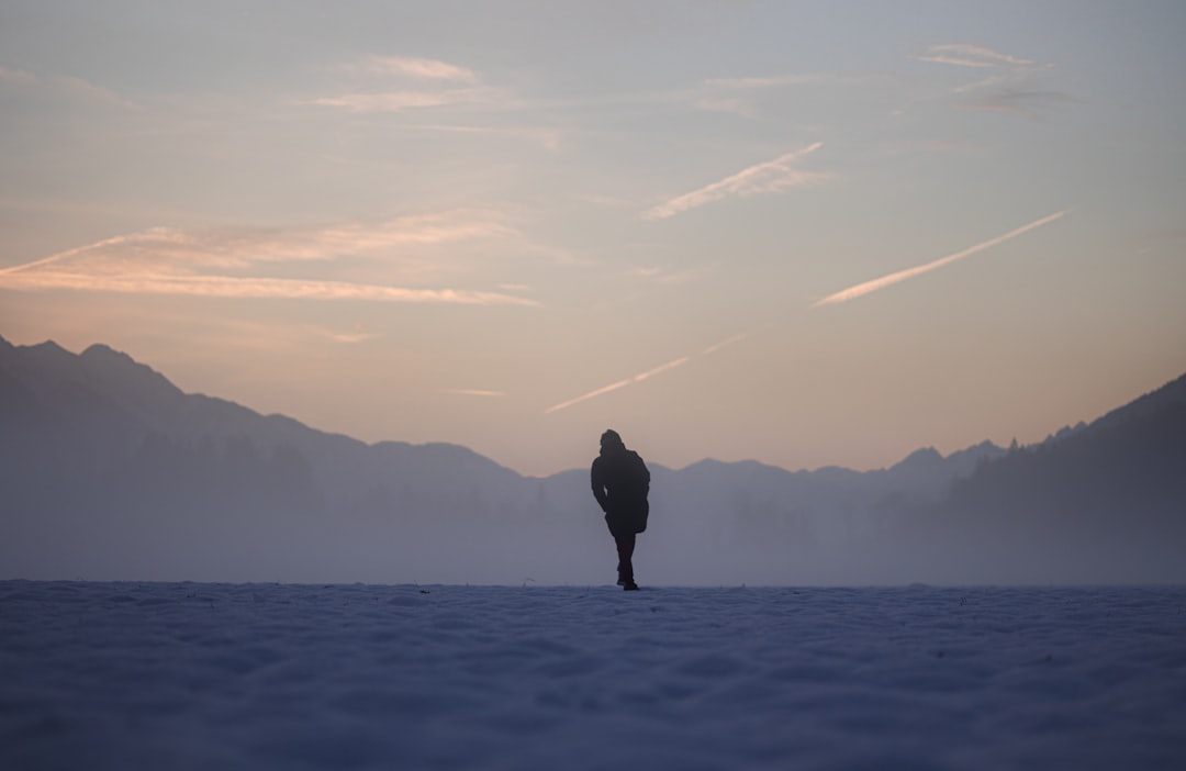 a person standing in the middle of a snowy field,