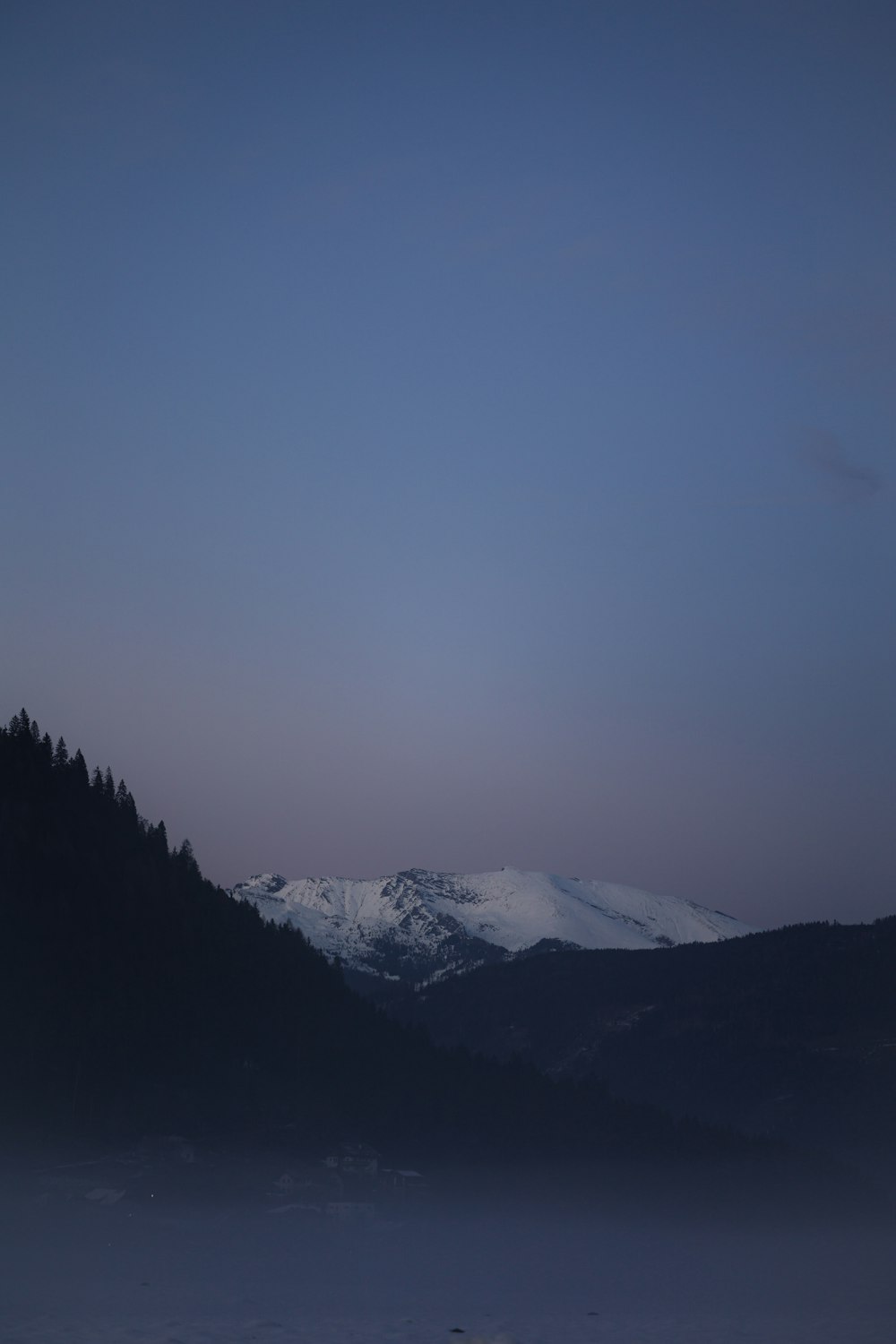 a view of a snowy mountain range at dusk