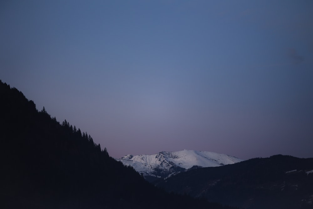 a view of a snowy mountain range at dusk