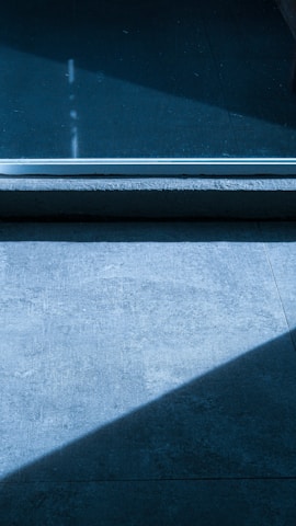 Close-up of a sleek vitrified tile with natural stone texture reflecting soft ambient light.