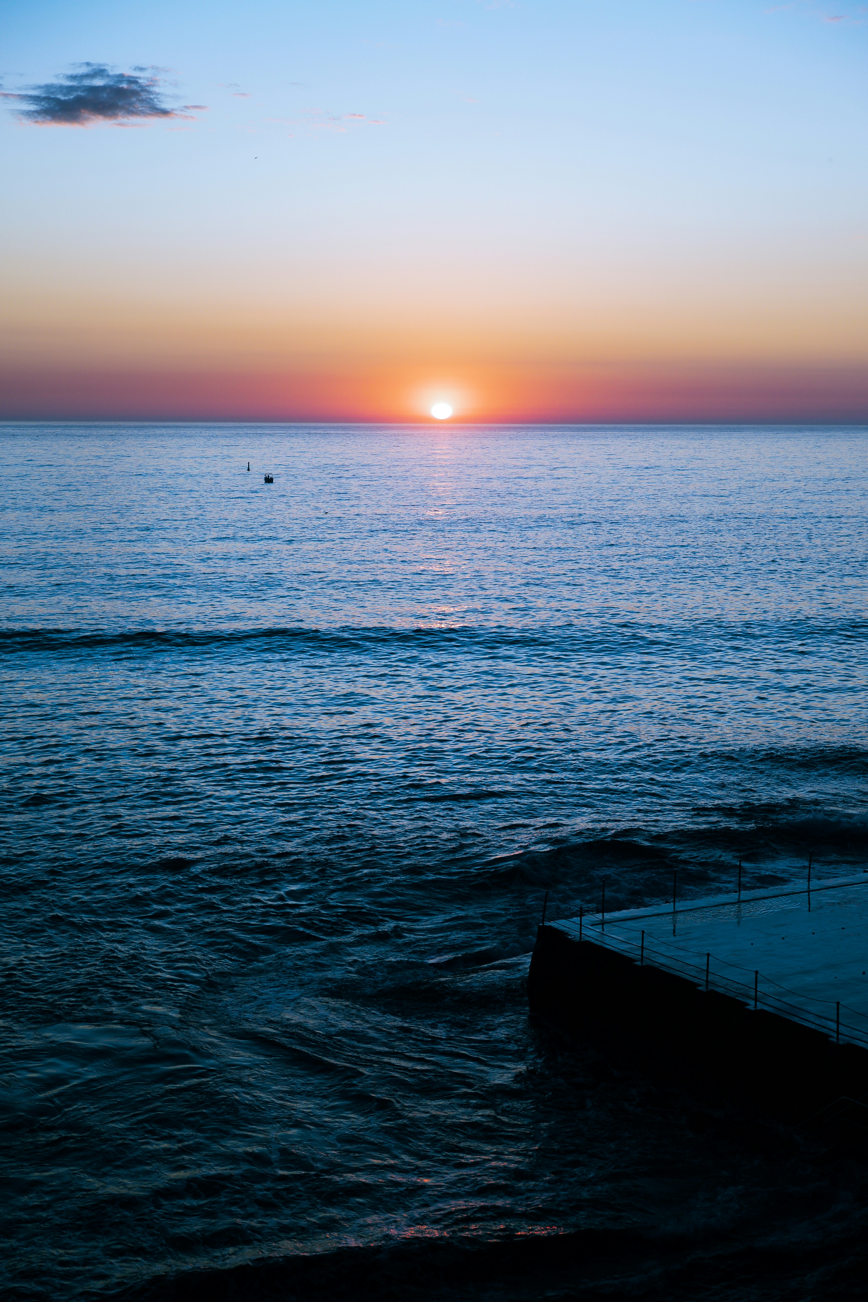 El sol se está poniendo sobre el océano con un muelle en primer plano