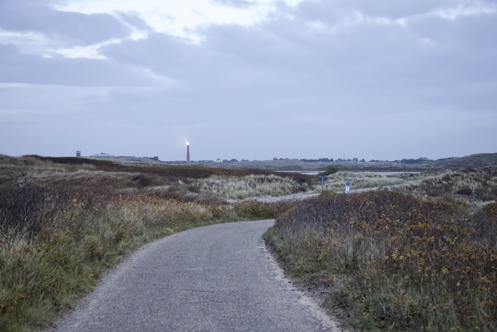 Un camino en un campo con una torre de luz en la distancia