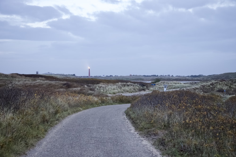 a road in a field with a light tower in the distance