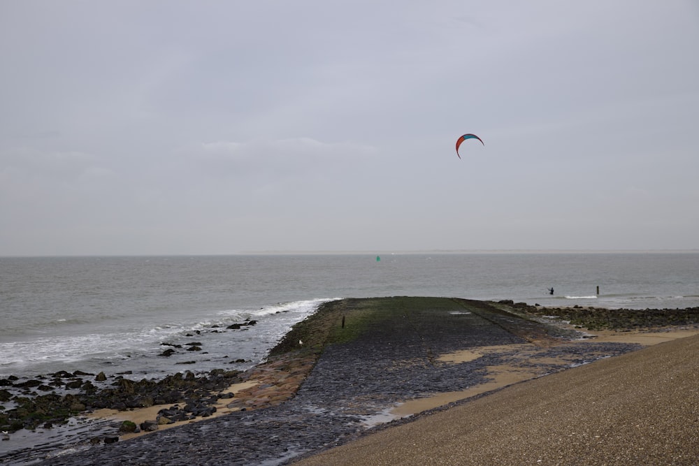 a kite flying over the ocean on a cloudy day