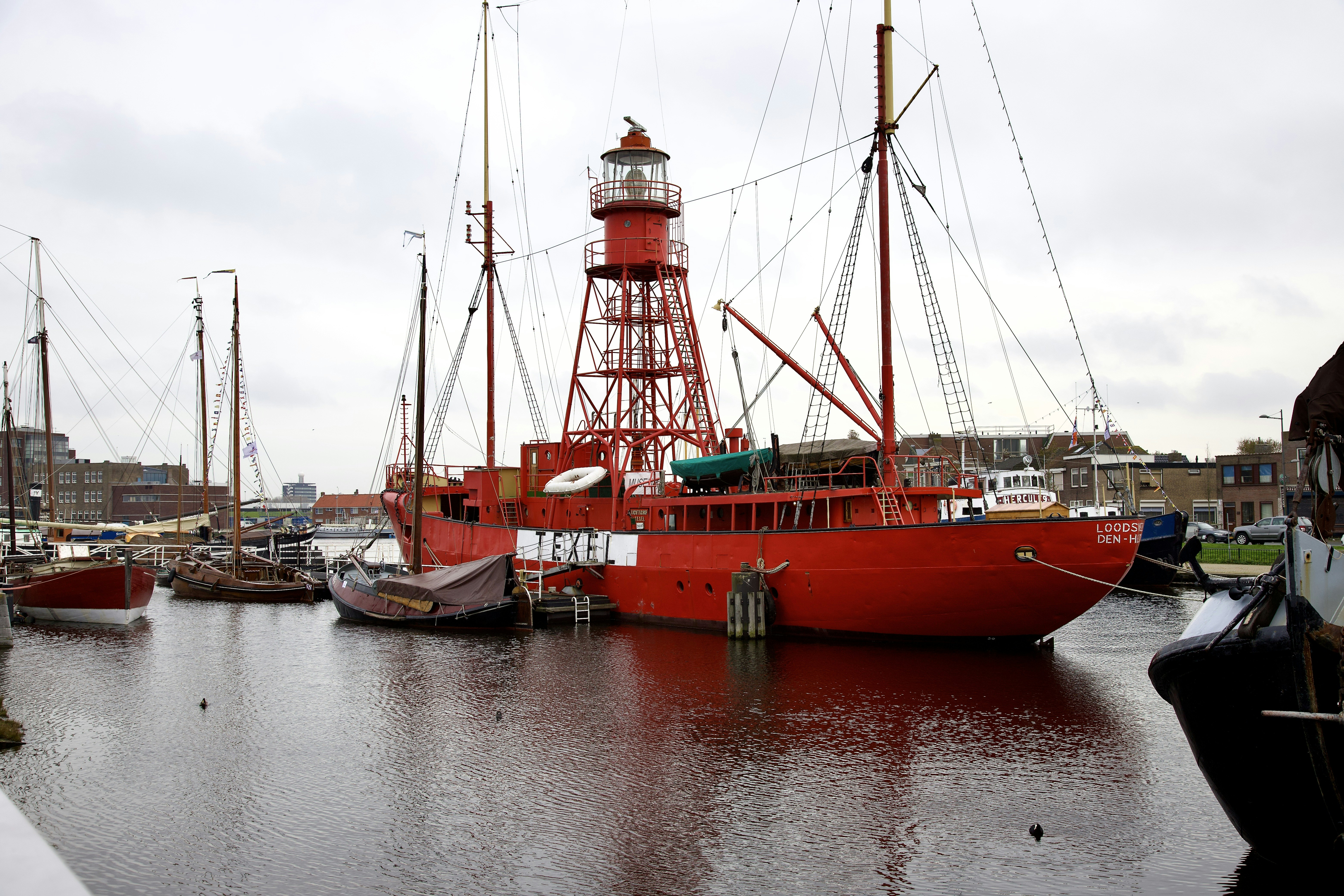 a red boat docked in a harbor next to a light house