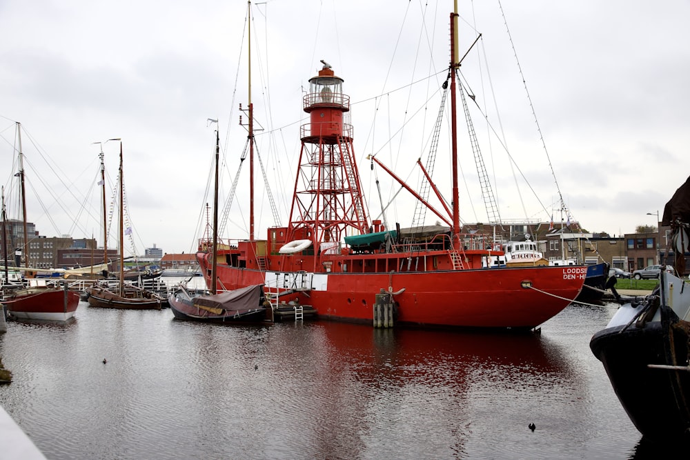 a red boat docked in a harbor next to a light house