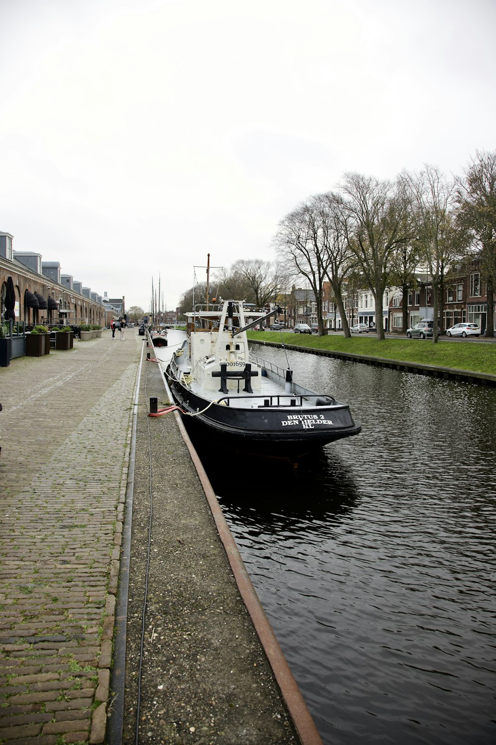 a black and white boat sitting on the side of a river