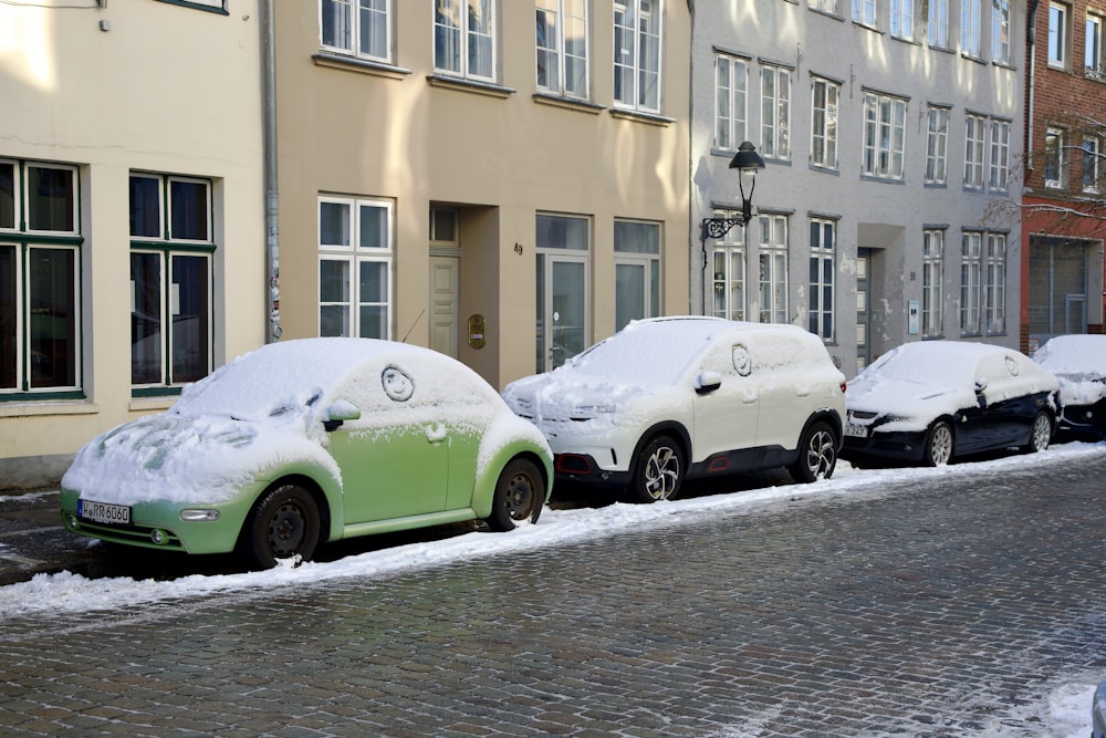 a row of parked cars covered in snow
