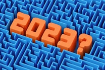 Large, bold orange numbers and a question mark in 3D text appear to rise from a complex blue maze, suggesting uncertainty or questioning related to the year 2023.