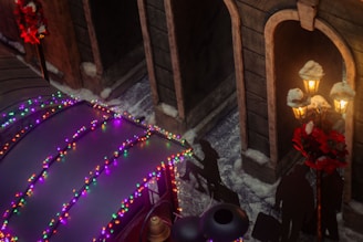 A street scene adorned with festive holiday lights in various colors on a structure or vehicle roof. Shadows of people walking with luggage are cast on the ground. Traditional lampposts decorated with red wreaths and snow provide a warm glow. The area is covered with patches of snow, enhancing the winter atmosphere.