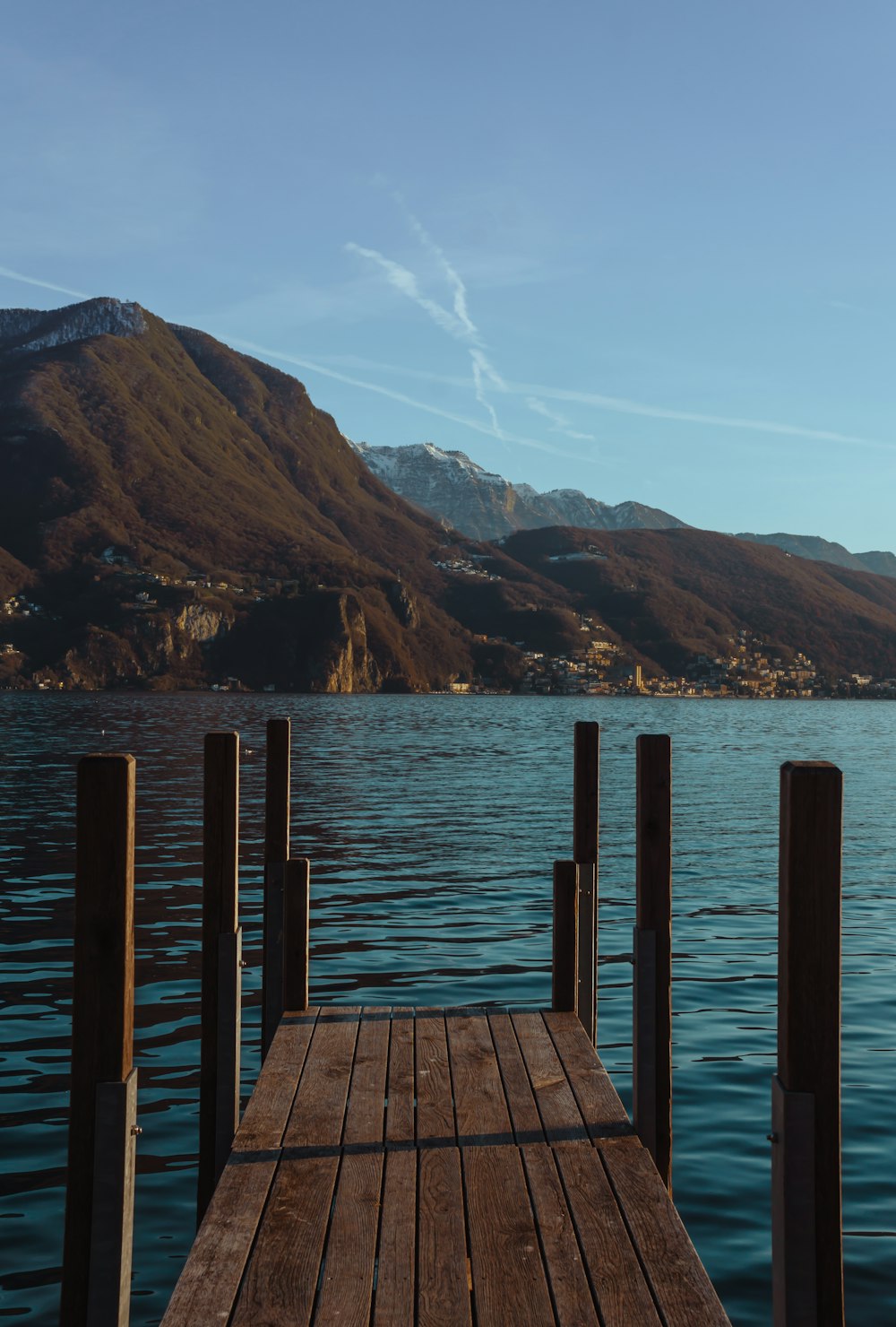 a wooden dock on a lake with mountains in the background