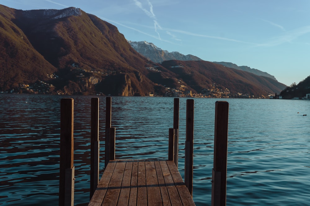 a wooden dock on a lake with mountains in the background