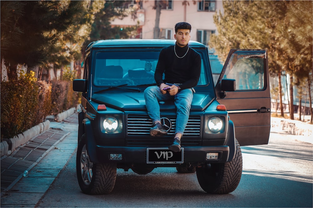 a man sitting on the hood of a mercedes benz benz benz benz benz benz benz