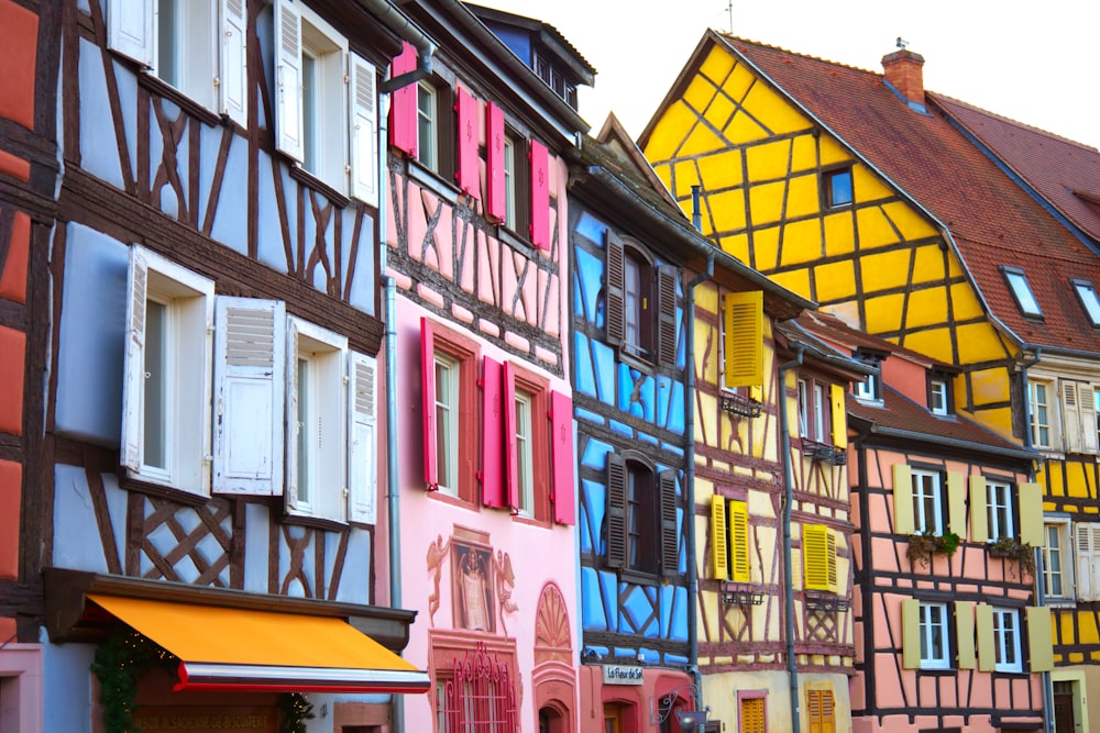 a row of multicolored buildings with windows and shutters