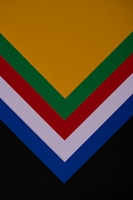 Several layers of colored paper arranged in a V shape, featuring colors such as yellow, green, red, white, blue, and black.