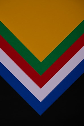 Several layers of colored paper arranged in a V shape, featuring colors such as yellow, green, red, white, blue, and black.