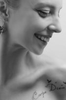 Close-up of a fan smiling with a freshly applied tatuflags tattoo on their cheek.