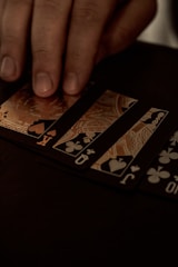 A hand drawing a card from a deck on a wooden table, soft warm lighting.