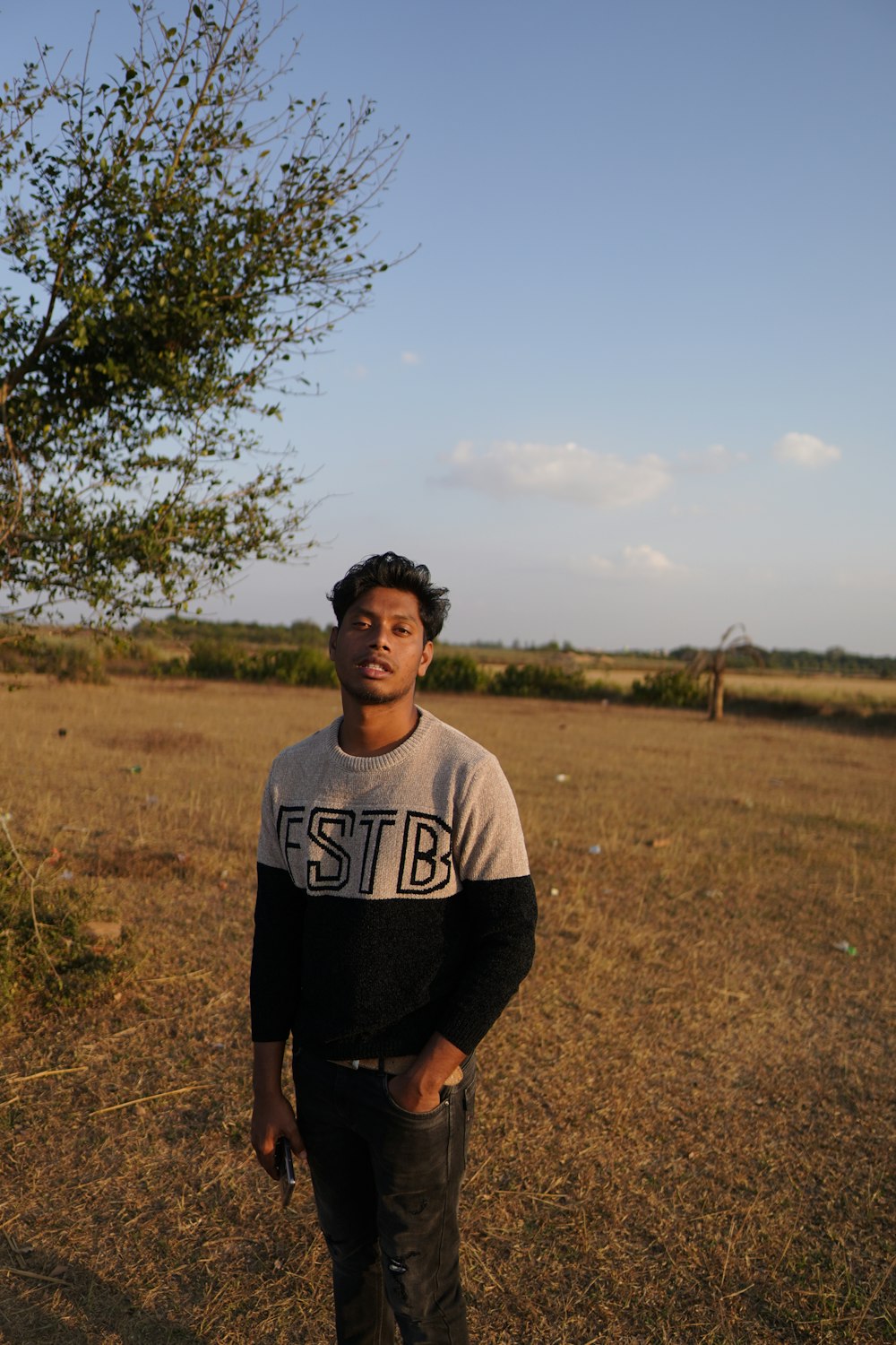 a man standing in a field with a tree in the background