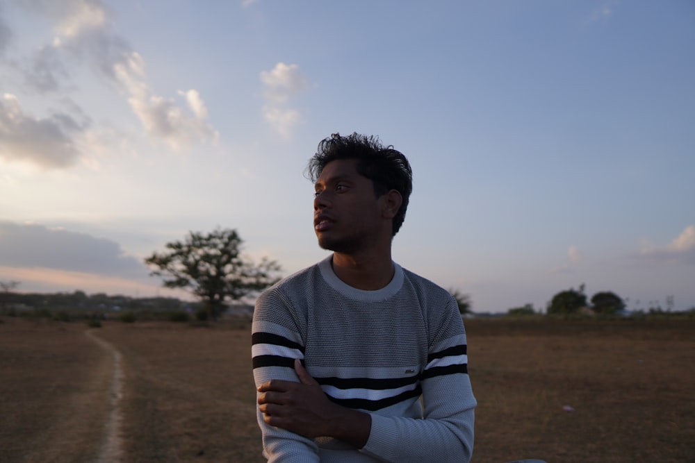 a man sitting in a field with his arms crossed