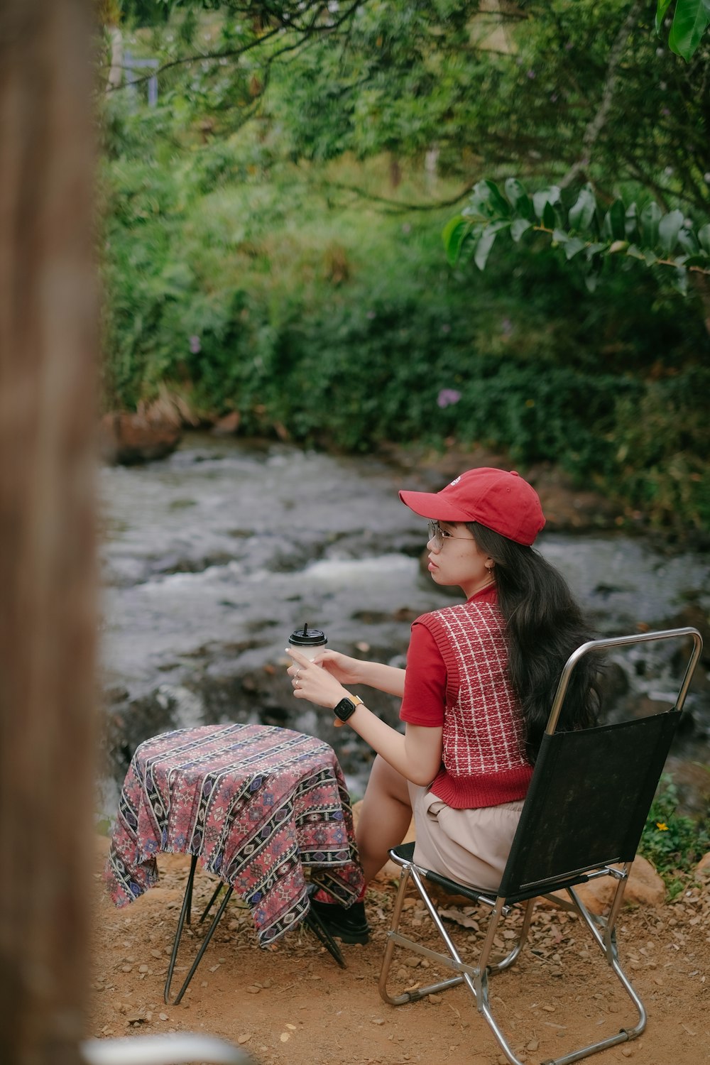 a woman sitting in a chair next to a river
