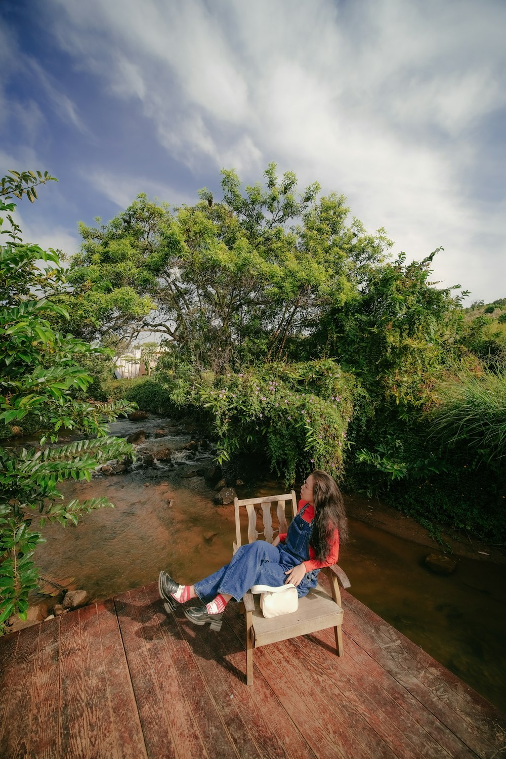 two people sitting on a bench near a river
