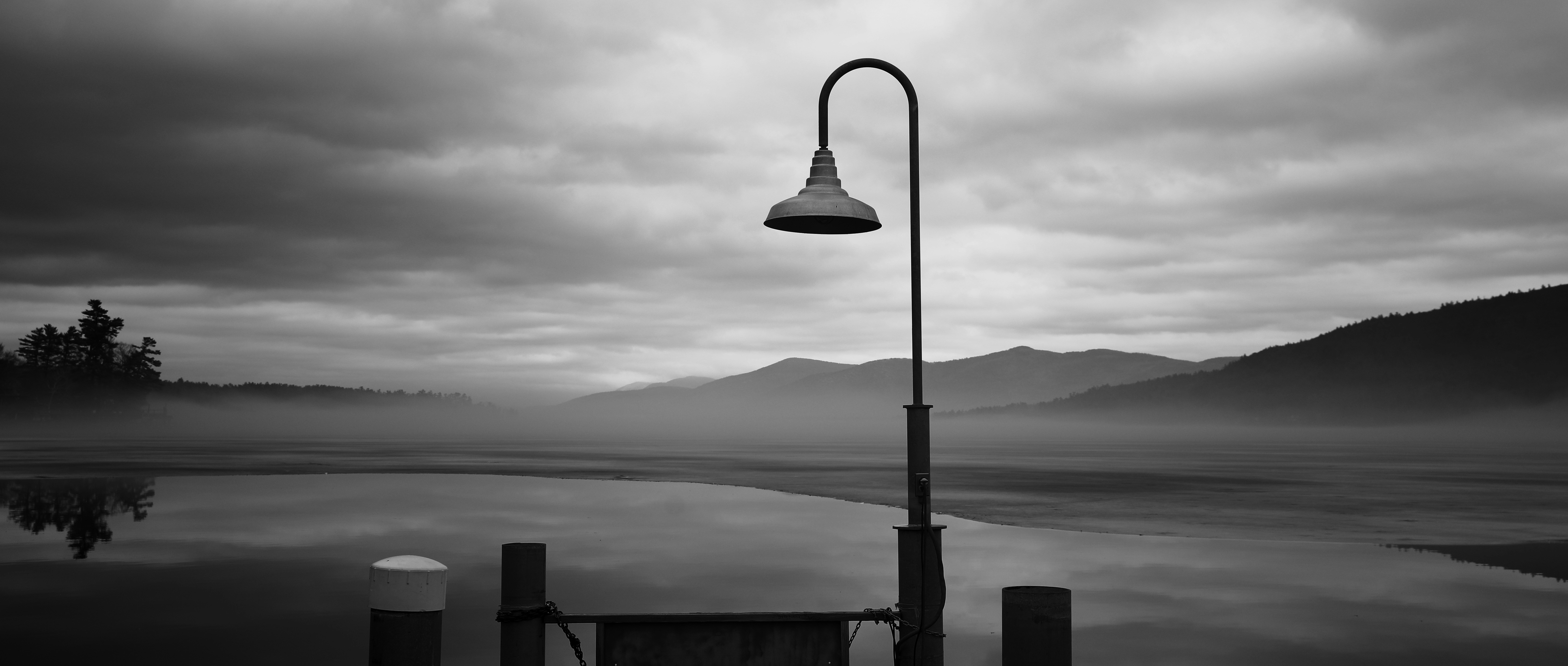 un poste de luz sentado junto a un cuerpo de agua