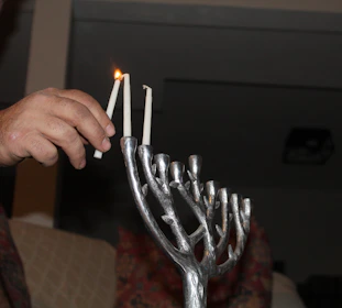 Hands lifted in worship beneath the light of a seven-branch menorah.