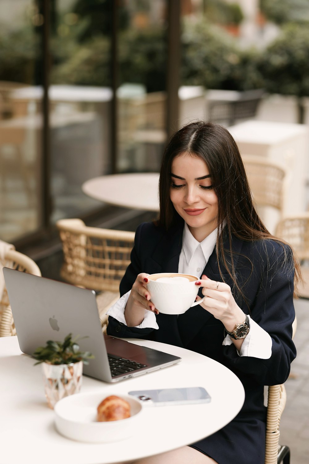 a woman sitting at a table with a laptop and a cup of coffee