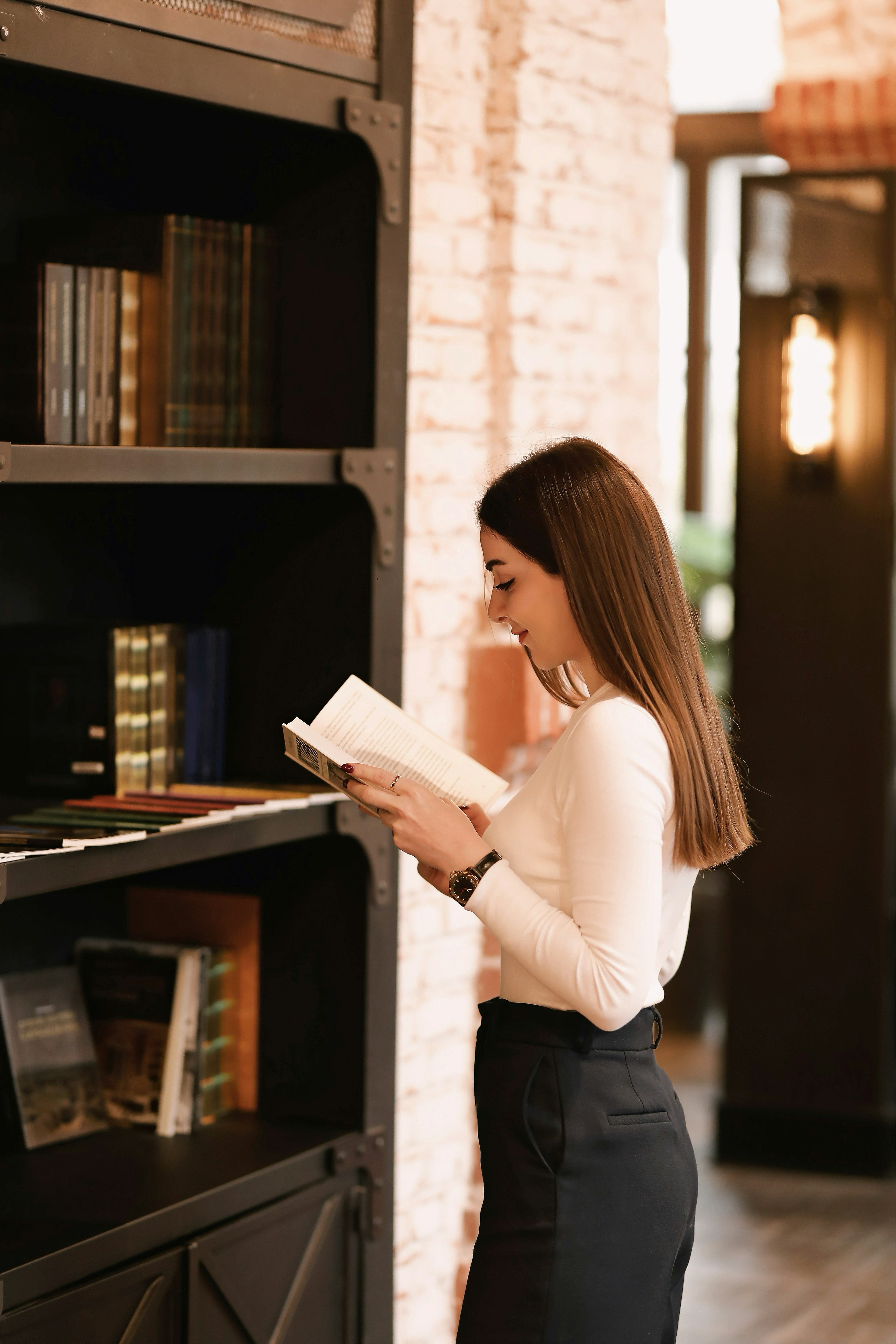 a woman reading a book in front of a bookcase